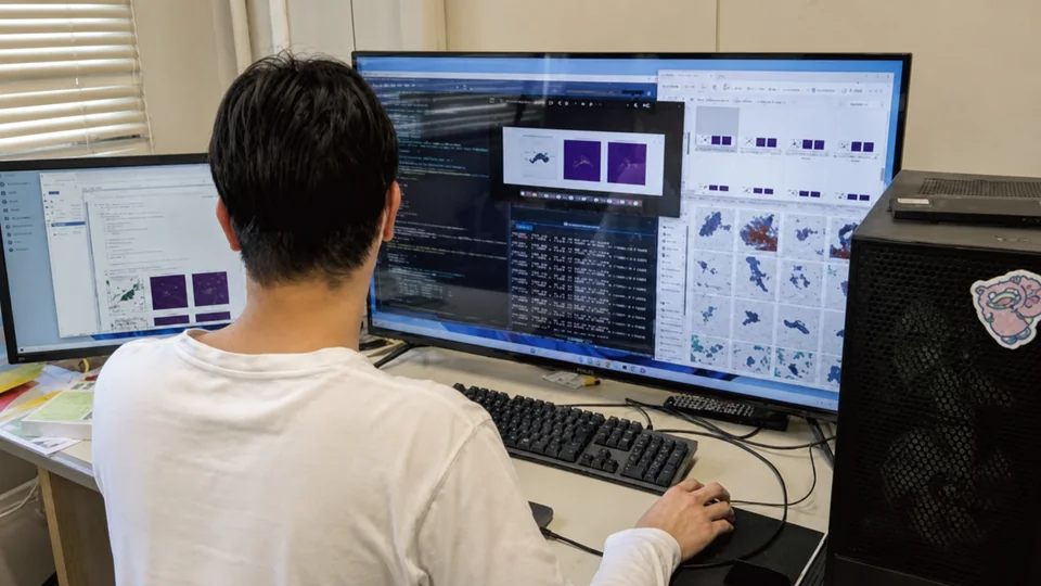 知能情報コースの学生が複数のモニターを使って画像解析とプログラミングに取り組む様子